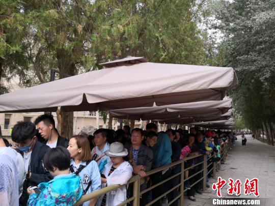 图为8月中旬,莫高窟前等候参观的应急游客排成近1公里的长队。 冯志军 摄