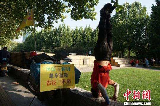 刘成义在街头倒立,吸引路人的目光宣传低碳出行。 韩章云 摄
