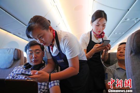 乘务员们在客舱内为旅客调试机上上网功能。 殷立勤 摄
