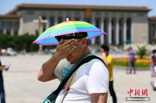 游客在高温下擦汗。中新社发 李慧思 摄