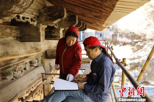 吴书瑞(右)和王菊花探讨工程施工情况。首都文明办供图