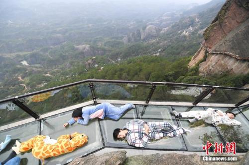 资料图:2017年3月21日,正值世界睡眠日,游人身着卡通睡衣躺在湖南平江石牛寨的悬崖玻璃栈道上,摆出各种睡姿享受睡眠,以此行为艺术呼吁关注睡眠健康。 杨华峰 摄