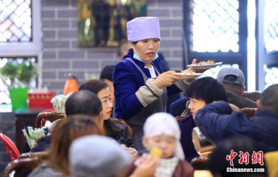 宁夏吴忠杨德福早茶拉面店的服务员为顾客端菜。中新社记者 杜洋 摄