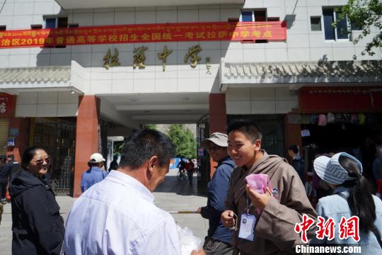 图为6月9日,家长在拉萨中学考点外为结束高考的孩子献哈达。 张伟 摄