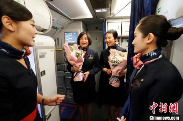客舱乘务员为吉晓春(左)和马文菁(右)献上鲜花。 殷立勤 摄