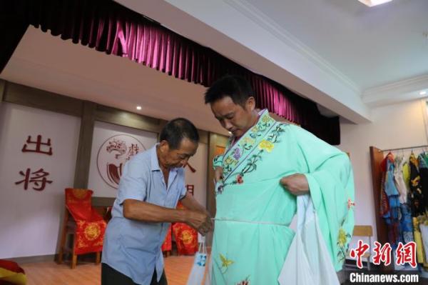 图为彭泽高腔剧团演员在表演前穿上戏服。 袁昕 摄